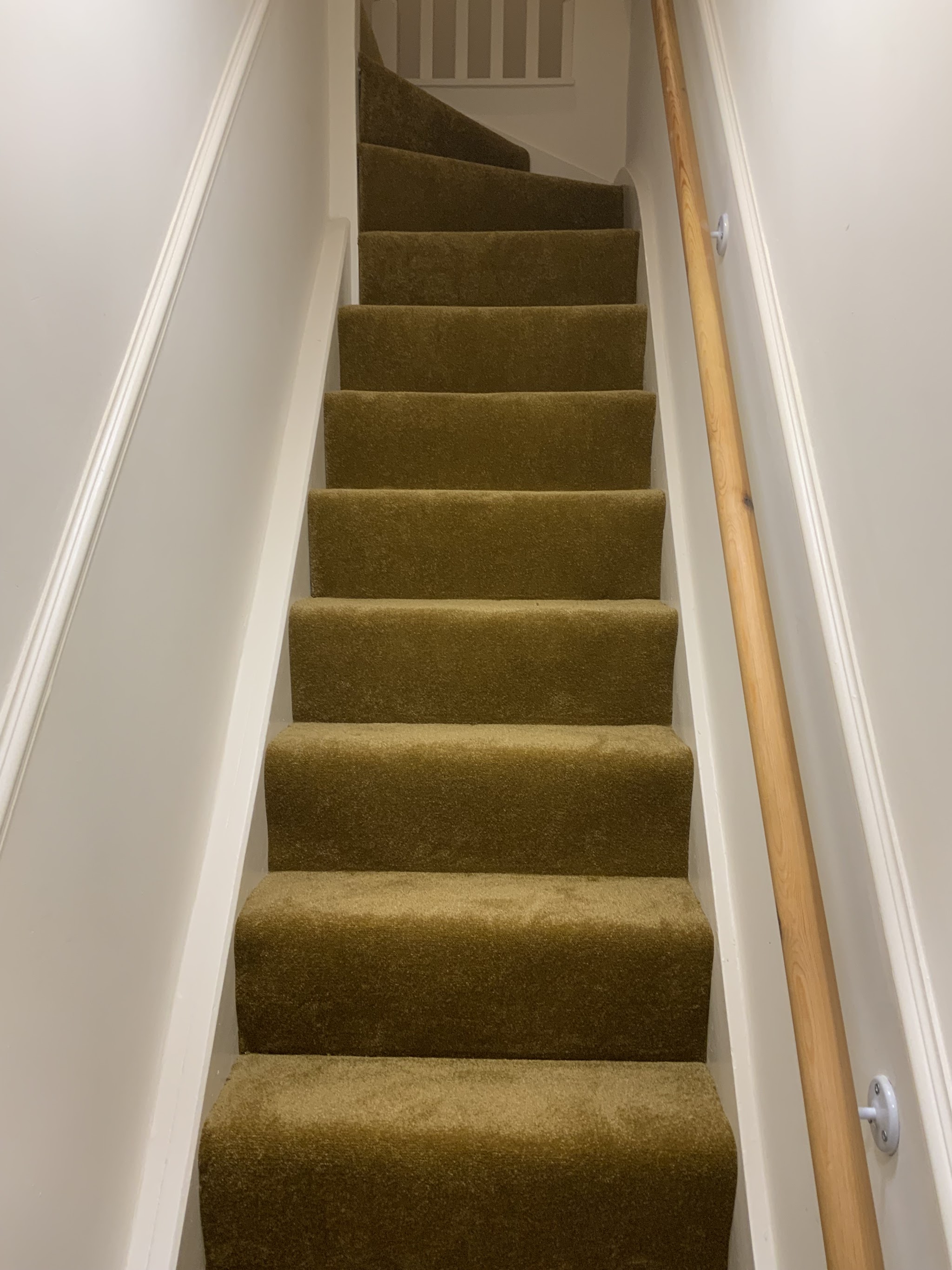 A full view up a mustard carpeted staircase